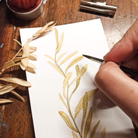 Photo d'un dessin de feuilles à l'aquarelle, avec ma main qui tient le pinceau et la feuille qui a servi de modèle.